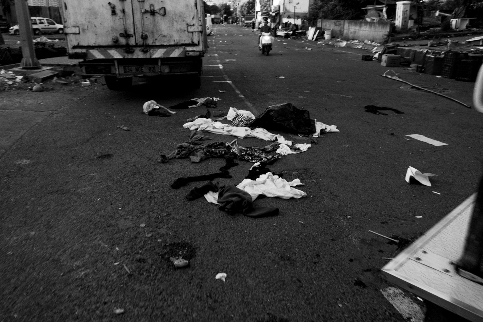 Clothes scattered across an empty market street, in black and white